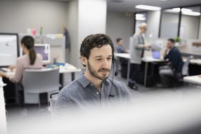 Salesman talking on telephone with headset at cubicle