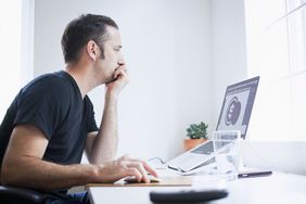Man at desk looking at a computer screen with a dollar sign on it