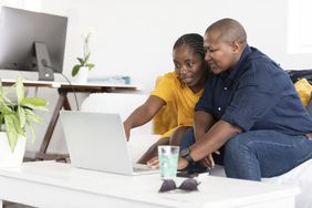 A couple looks at a laptop while sitting on a couch
