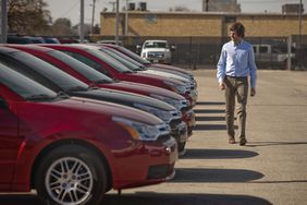A man looking at certified pre-owned cars in a car lot