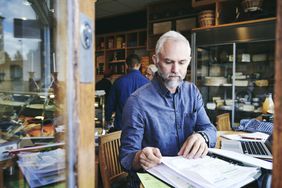 A small business owner sitting in a cafe works on accounting books