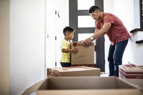 Parent and child lifting moving boxes in a new home