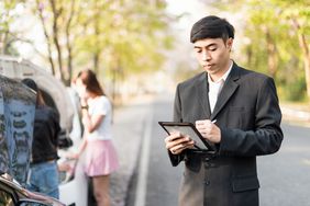 A person in business attire writes on a tablet.