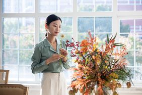 A person looks at a floral arrangement in a home.