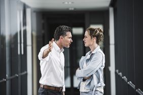 A man and a woman stand face to face in a business setting.