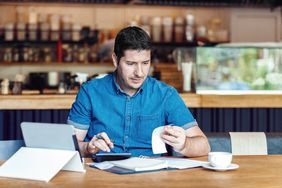 Small business owner doing paperwork and calculating expenses
