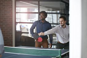 co-workers playing ping-pong in an office