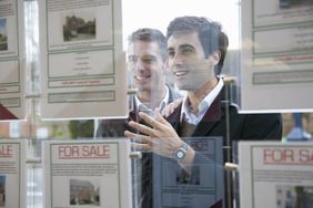 A couple looks at real estate flyers on an agency window