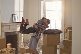 couple excited at being in their first home together hugging surrounded by boxes around