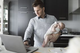 Man working while holding baby