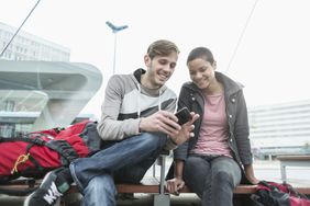 Young couple with smartphone at bus stop