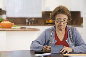 Woman writing checks in kitchen
