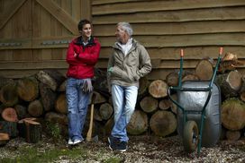 Father and son standing beside a woodpile outside a barn