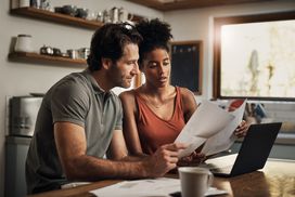 Couple looking at statements and working on laptop