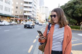Woman on a city street uses a crowdsourced app.
