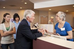 A line of patients waiting for help at a medical office front desk