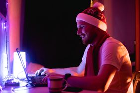 Happy man wearing Santa hat trades on laptop