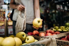A woman shops for apples at a produce market.