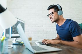 Person wearing headphones using multiple computers