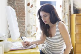 person in striped tank top writing something down at their desk