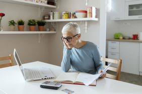 A mature woman reviews her retirement accounts on a laptop.