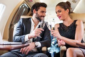 Couple of people having a champagne toast inside the private jet airplane