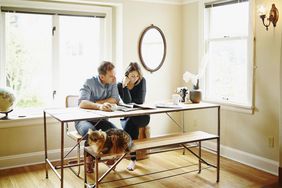 Couple at table in home reading newspaper together