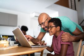 A father and son look at a computer.