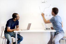 Two men discussing business goals at a white board