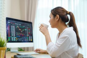 Person drinking coffee while looking at a trading screen
