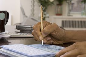 Elderly woman writing in a checkbook
